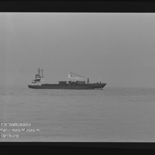 Schwarzweißfoto eines Frachtschiffs mit Ladebaum auf ruhiger See, unten links Schriftzug Maritimes Museum Hamburg