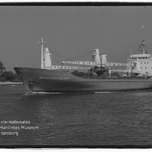 Frachtschiff mit markanten Ladekränen auf Küstengewässern, schwarzweiß-Aufnahme mit Internationales Maritimes Museum Hamburg-Logo.