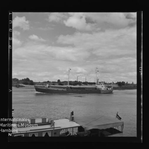 Frachtschiff auf Fluss vor flachem Ufer; im Vordergrund Boote und der Schriftzug Internationales Maritimes Museum Hamburg
