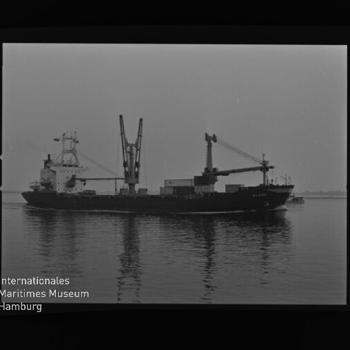 Beladenes Frachtschiff mit zwei Ladekränen in ruhigem Wasser, Schwarzweißfoto mit Museumssignet.