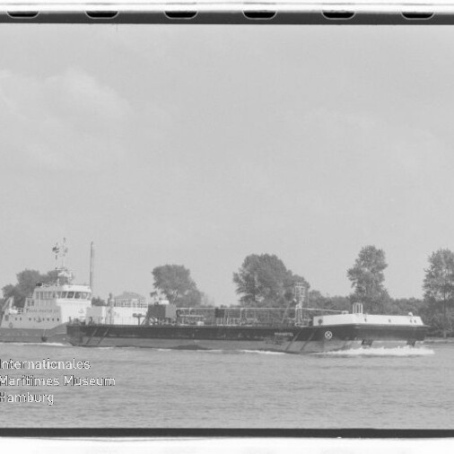 Schwarzweißaufnahme eines langen Tankbarges auf einem Fluss vor Bäumen; links Wasserzeichen Maritimes Museum Hamburg.