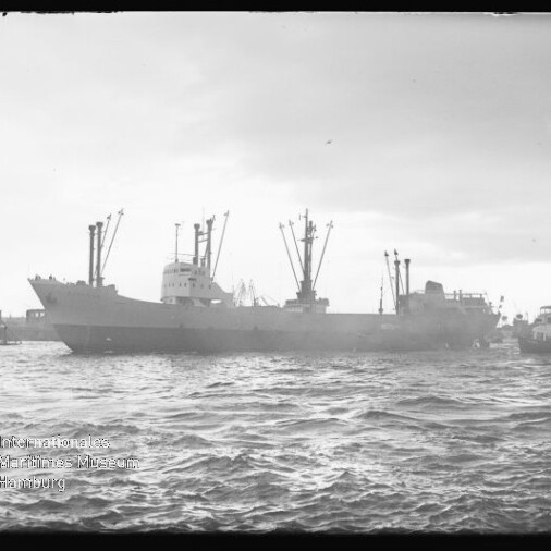Frachtschiff mit mehreren Ladekränen vor Hafen bei welliger See, Wasserzeichen des Internationalen Maritimen Museums Hamburg.