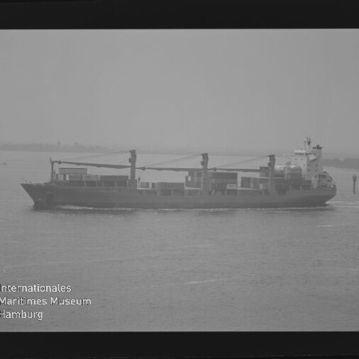 Frachtschiff mit drei Deckskränen auf ruhiger, nebeliger See; Wasserzeichen: Internationales Maritimes Museum Hamburg.
