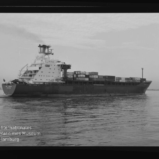 Schwarzweißaufnahme eines Containerschiffs mit gestapelten Containern auf ruhigem Wasser, Museumslogo unten links.