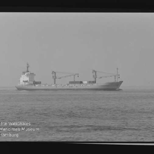 Schwarzweißfoto eines Frachtschiffs mit Ladekränen auf ruhiger See; Filmrand und Beschriftung AGFA PAN 100 sichtbar.
