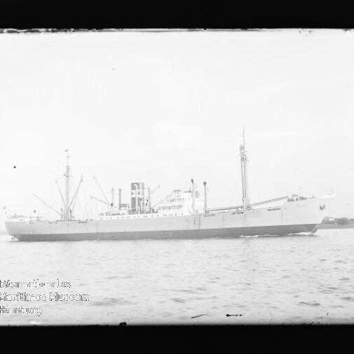Frachtschiff in Seitenansicht auf ruhiger See mit Ladekränen und Schornstein, schwarzweiß.