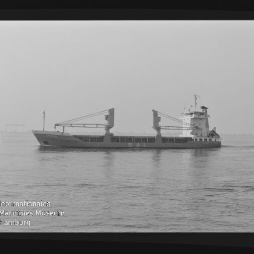Frachtschiff mit zwei Ladekränen und achterem Aufbauten fährt seitlich auf ruhiger See; Schwarzweißaufnahme mit Museumslogo.