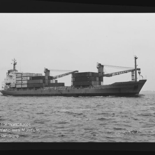 Containerschiff mit aufgestapelten Containern und zwei Ladekränen fährt auf ruhiger See; schwarzweiß mit Museumslogo.