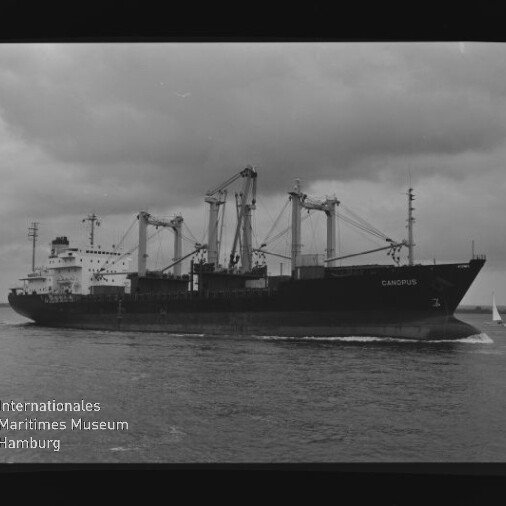 Frachtschiff CANOPUS mit Kränen unter bewölktem Himmel; Wasserzeichen Internationales Maritimes Museum Hamburg.