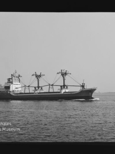 Frachtschiff mit drei Ladekränen fährt seitlich auf ruhiger See, schwarzweißes Foto mit Wasserzeichen des Maritimen Museums.