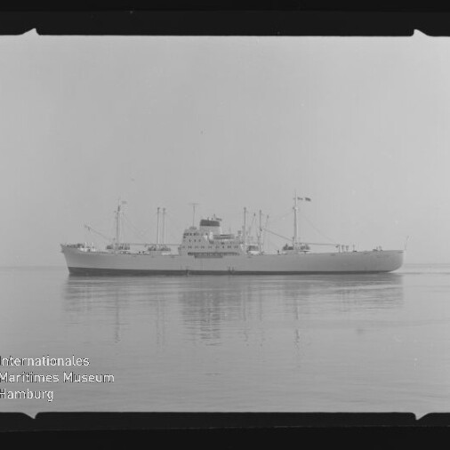 Schwarzweißfoto eines Frachtschiffs mit Aufbauten und Kränen auf spiegelglattem Meer, Stempel des Internationalen Maritimen Museums Hamburg.
