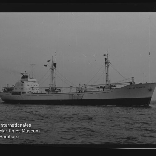 Frachtschiff mit zwei Lademasten und Brückenaufbau fährt auf ruhiger See; Museumswasserzeichen unten links.