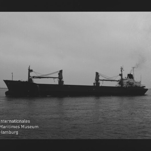 Schwarzweiß-Silhouette eines Frachtschiffs mit zwei Ladekränen auf ruhiger See; Museumslogo Internationales Maritimes Museum Hamburg sichtbar.