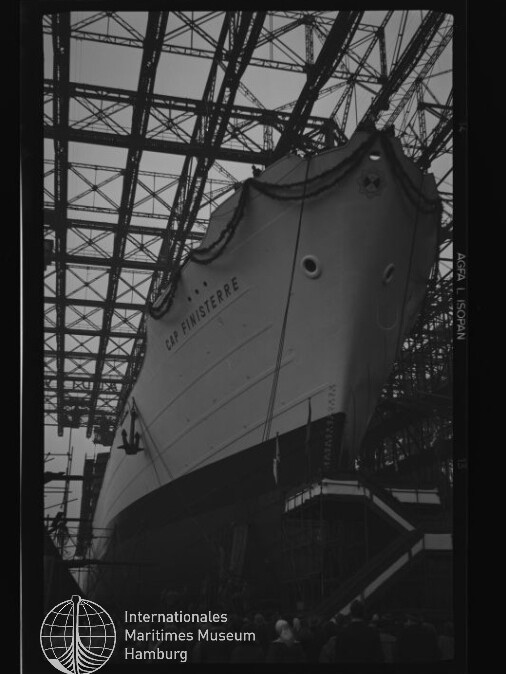 Bug des Passagierschiffs C.H. Finisterre im Trockendock unter einem großen Stahlgerüst, mit Girlanden und Zuschauern.