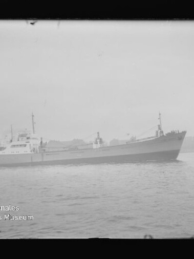 Schwarzweißfoto eines Frachtschiffs seitlich auf ruhigem Wasser, mit Wasserzeichen Internationales Maritimes Museum Hamburg.