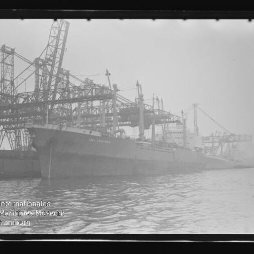 Frachtschiff am Industriehafen bei Nebel, von großen Ladekränen gesäumt; Wasserzeichen: Internationales Maritimes Museum Hamburg