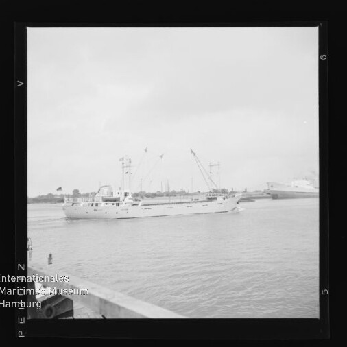 Weißes Frachtschiff mit Masten fährt am Kai vorbei; links unten Wasserzeichen Internationales Maritimes Museum Hamburg.