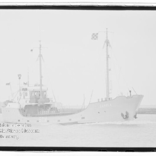 Schiff mit zwei Masten und Flagge fährt auf ruhiger See; Wasserzeichen unten links.
