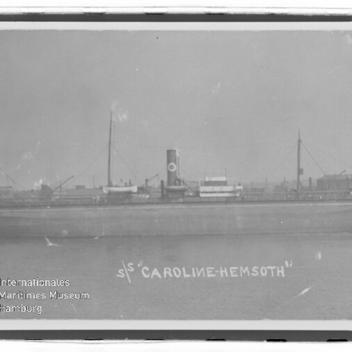 Seitliche Aufnahme des Dampfschiffs S/S Caroline-Hemsoth mit mittigem Schornstein, zwei Masten und ruhigem Wasser.