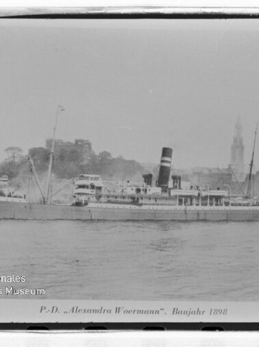 Historisches Passagierdampfschiff Alexandra Woermann (Baujahr 1898) seitlich auf dem Wasser, Ufer mit Gebäuden im Hintergrund.