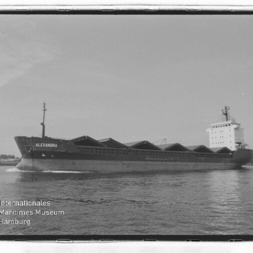 Frachtschiff ALEXANDRIA in Schwarzweiß mit spitzen Ladeluken auf ruhigem Wasser, Museumsstempel links unten