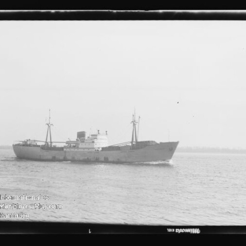 Schwarzweiß-Foto eines Frachtschiffs im Seitenprofil auf ruhiger See, Filmrand und Museumslogo links unten.