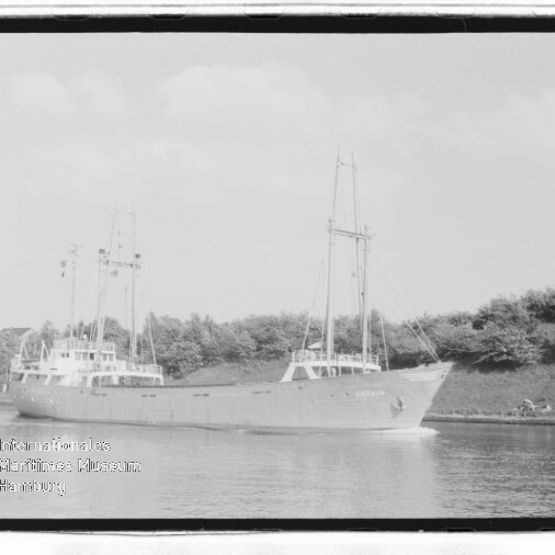 Zweimastiges Frachtschiff auf ruhigem Kanal vor Bäumen, mit Wasserzeichen des Internationalen Maritimen Museums Hamburg.