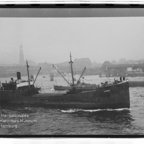 Frachtschiff fährt in Hafen mit nebliger Stadtkulisse und Kirchturm im Hintergrund, Museumswasserzeichen unten links.