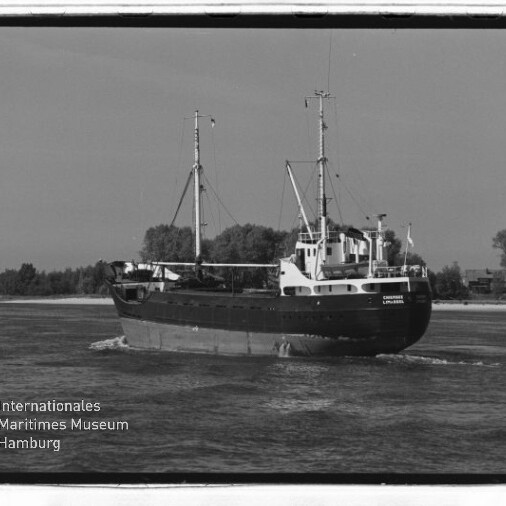 Schwarz-weiß-Foto eines Frachtschiffs mit zwei Masten auf einem Fluss, Ufer und Bäume im Hintergrund; Museumslogo links unten