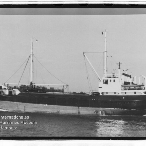 Schwarzweißaufnahme eines Frachtschiffs mit zwei Masten und Aufbauten, fahrend auf ruhigem Wasser; Museumslogo unten links.