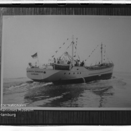 Gerahmtes Schwarzweißfoto eines geschmückten Schiffes mit Flaggen über ruhiger See und Museumswasserzeichen.