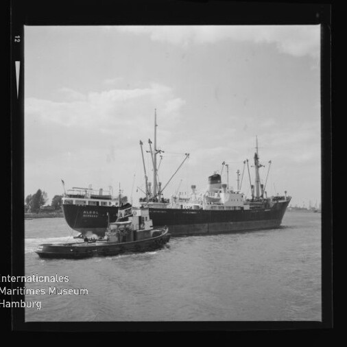 Schlepper neben großem Frachtschiff in Schwarzweißaufnahme, Wasserzeichen Internationales Maritimes Museum Hamburg