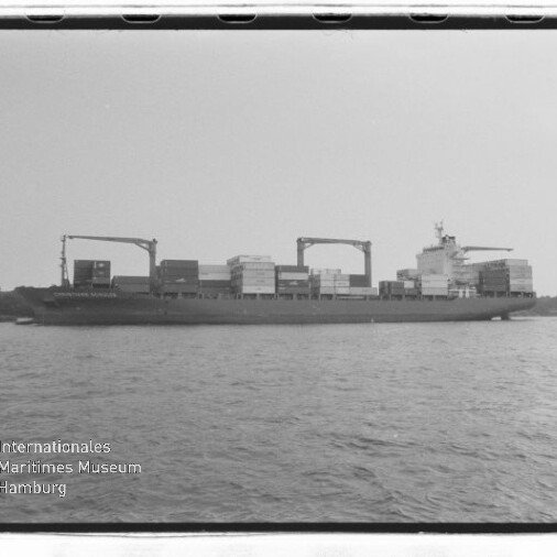 Frachtschiff mit Containern und zwei Ladekränen auf ruhiger See; Wasserzeichen des Internationalen Maritimen Museums Hamburg.