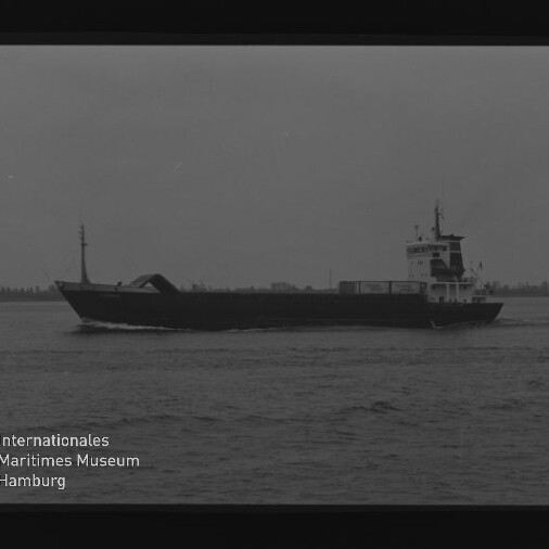 Schwarzweiß-Foto eines Frachtschiffs in Profilfahrt auf ruhiger See, mit Museumslogo und Text unten links.