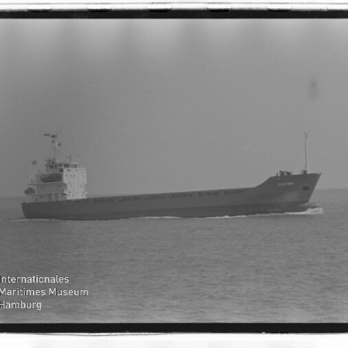 Frachtschiff in Seitenansicht auf ruhiger See, Schwarzweißaufnahme mit Museumslogo unten links.