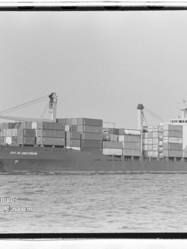 Schwarzweißaufnahme eines Containerschiffs City of Amsterdam mit gestapelten Containern und Deckskränen auf hoher See.