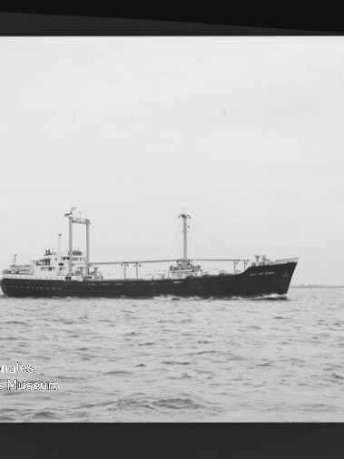 Frachtschiff mit zwei Ladekränen auf ruhiger See, s/w-Foto mit Wasserzeichen des Maritimen Museums Hamburg.