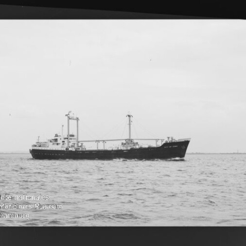 Frachtschiff mit zwei Ladekränen auf ruhiger See, s/w-Foto mit Wasserzeichen des Maritimen Museums Hamburg.