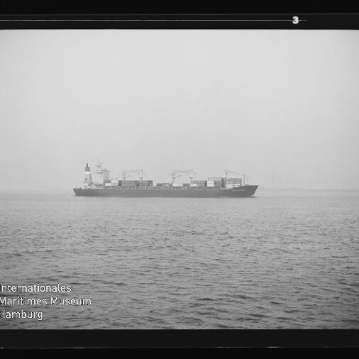 Containerschiff auf ruhiger, nebliger See am Horizont; linkes unteres Wasserzeichen Internationales Maritimes Museum Hamburg