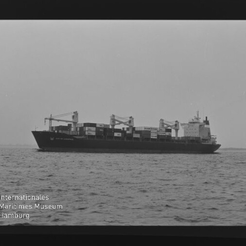 Schwarzweiß-Seitenansicht eines Containerschiffs mit gestapelten Containerboxen und Ladekränen auf ruhiger See.