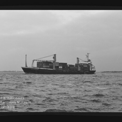 Containerfrachter mit Containern und Ladekränen auf ruhiger See; Museumslogo unten links.