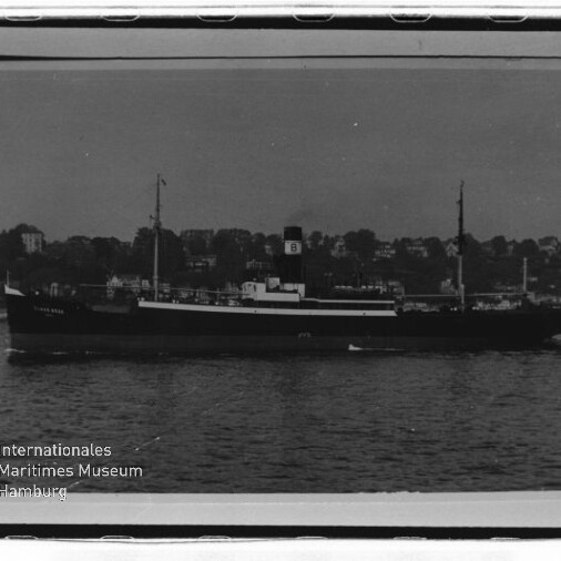 Frachtschiff mit Schornstein und zwei Masten vor einem Ufer mit Häusern, unten links Schriftzug Maritimes Museum Hamburg.