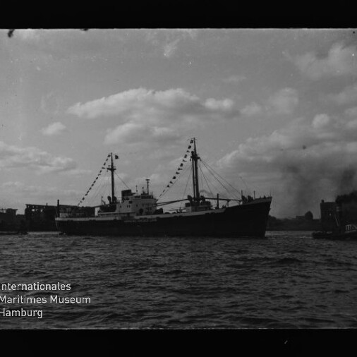 Silhouette eines geschmückten Frachtschiffs mit Wimpelgirlanden auf dem Wasser, kleiner Schlepper rechts, Museumlogo unten links.