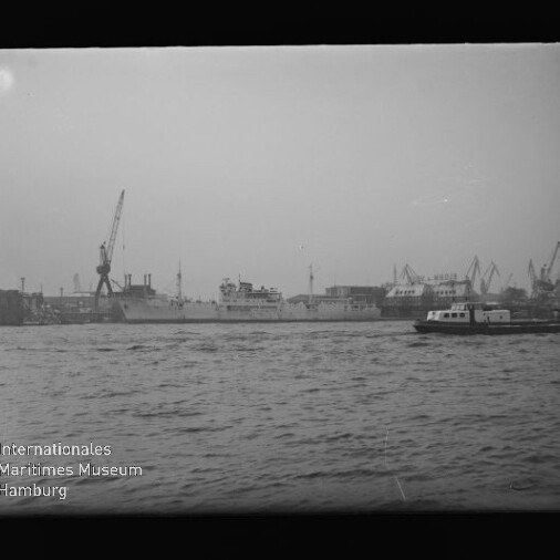 Hafenpanorama mit Schiffen, Kränen und einer kleinen Fähre; sichtbarer Schriftzug: Internationales Maritimes Museum Hamburg.