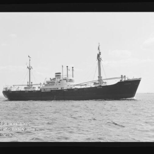 Schwarzweißfoto eines Frachtschiffs mit zwei Masten auf ruhiger See, Wasserzeichen Museum Hamburg sichtbar.