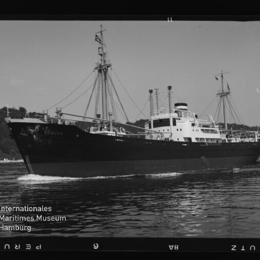 Schwarzweiß-Foto eines Frachtschiffs mit Masten und Aufbauten auf ruhiger See, Museumswasserzeichen links unten.