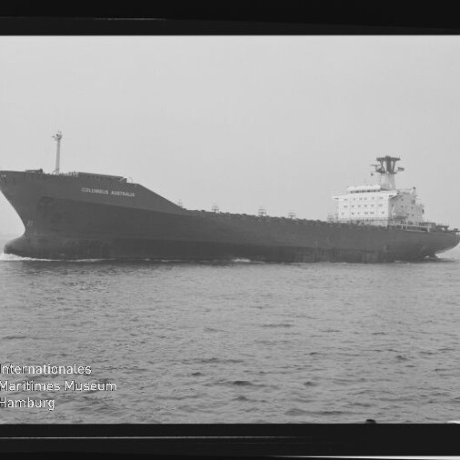 Schwarzweiß-Seitenansicht eines großen Frachtschiffs namens „Columbus Australia“, das ruhig über die See fährt; das Bild ist wie ein Filmnegativ mit Randmarkierungen und Wasserzeichen des Internationalen Maritimen Museums Hamburg gerahmt.