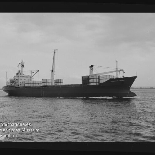 Schwarzweiß-Foto eines Frachtschiffs mit gestapelten Containern und zwei Ladekränen, das auf ruhiger See entlangfährt; am unteren linken Rand das Logo des Internationalen Maritimen Museums Hamburg und schwarzer Filmrand sichtbar.