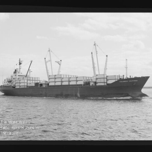 Frachtschiff mit aufgestapelten Containerreihen und mehreren Ladekränen fährt auf ruhigem Meer unter leicht bewölktem Himmel; unten links sichtbar das Logo des Internationalen Maritimen Museums Hamburg.