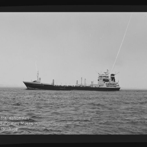 Schwarzweißaufnahme eines Tankers in Seitenansicht auf ruhiger See mit weitem Horizont, sichtbarem Filmbandrand und Museumswasserzeichen unten links.